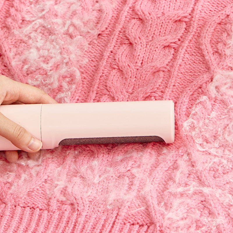 Pet hair remover brush gliding across a pink knit sweater to lift fur and lint