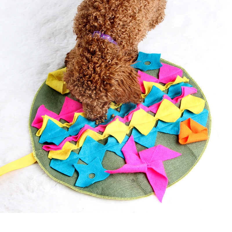 Curly-coated dog sniffing a round snuffle mat with colorful fabric flaps